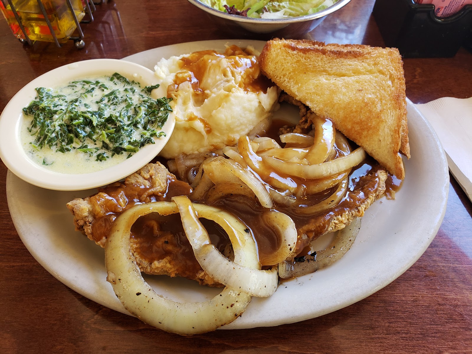 Chicken fried steak plate with creamed spinach, mashed potatoes, and toast